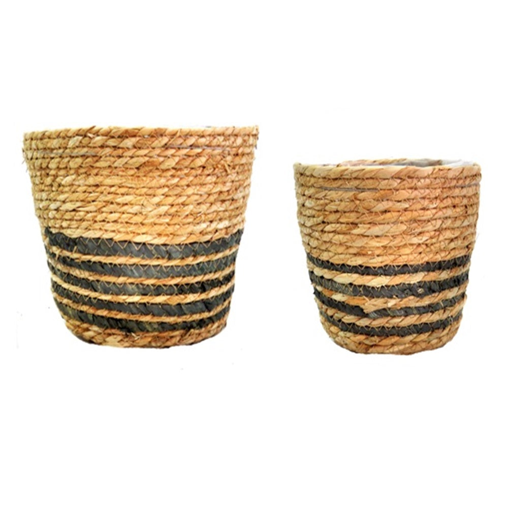 These Catalan Baskets S/2 are hand-woven with natural materials and lined with plastic for durability. The thin black stripes add an attractive touch, making these baskets not only useful, but also aesthetically pleasing. The set includes two sizes: 22cm top diameter x 18cm height for the larger basket and 17.5 cm top diameter x 15cm height for the smaller basket. Perfect for all your planter needs-unique interiors